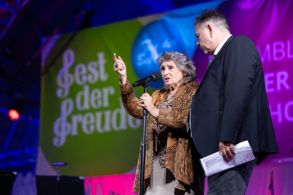 Rosa Schneeberger und ihr Sohn stehen auf eine Bühne und blicken in die Menge beim Fest der Freude.